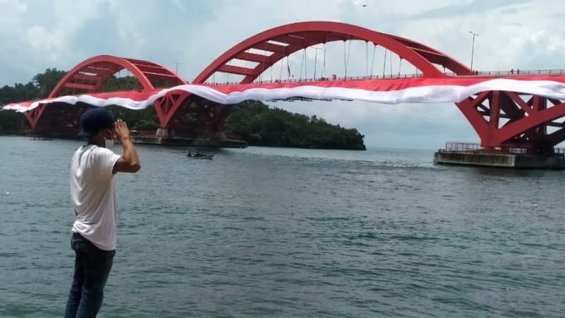 Bersinergi dengan Warga Papua, Banser Bentangkan Bendera di Jembatan Merah Youtefa